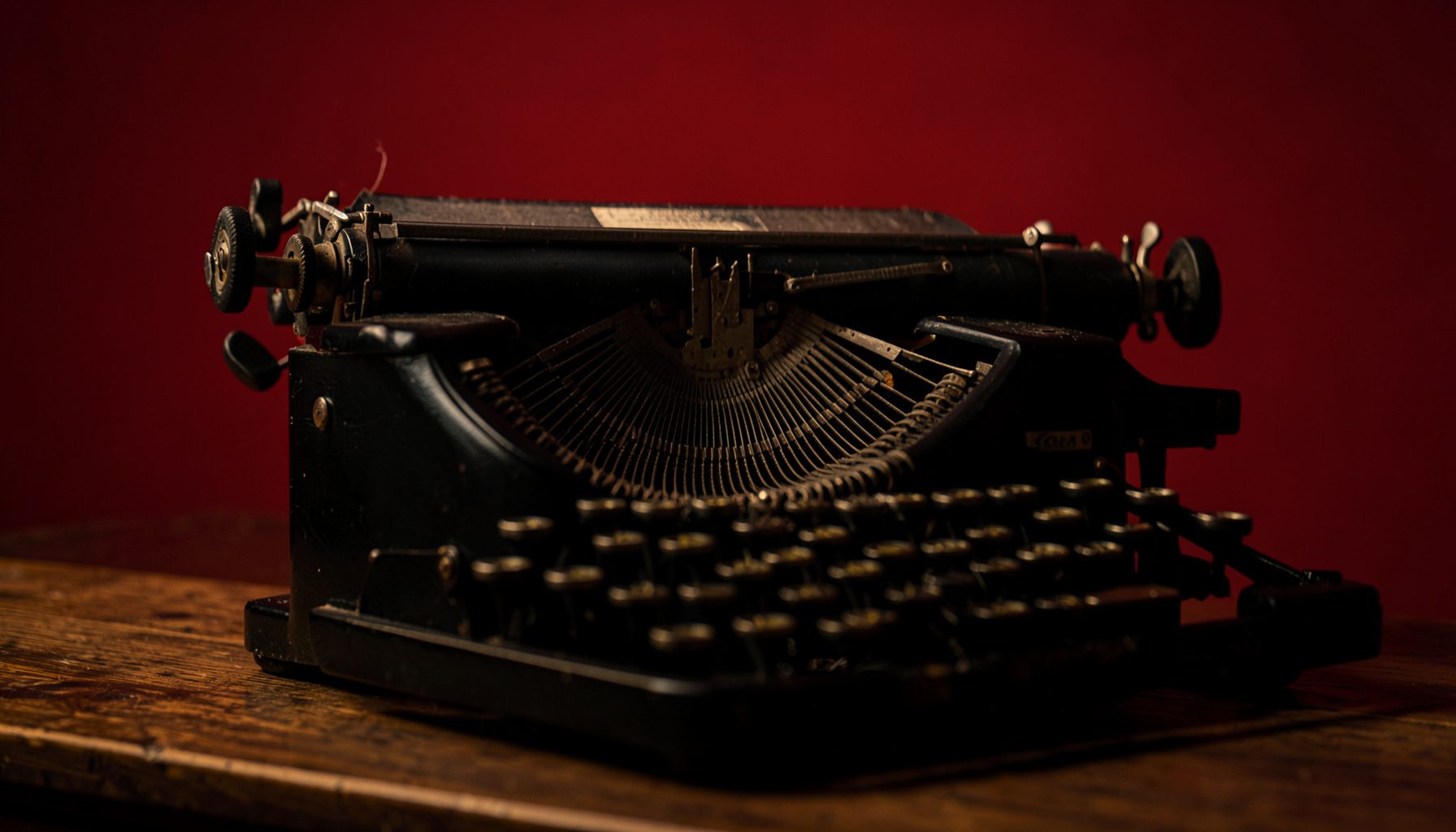 Darkened close-up of a vintage typewriter on a wooden desk, warm amber and deep brown tones, moody and literary atmosphere.